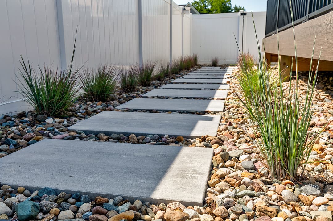 Modern garden pathway with stone slabs, decorative gravel, and ornamental grass.
