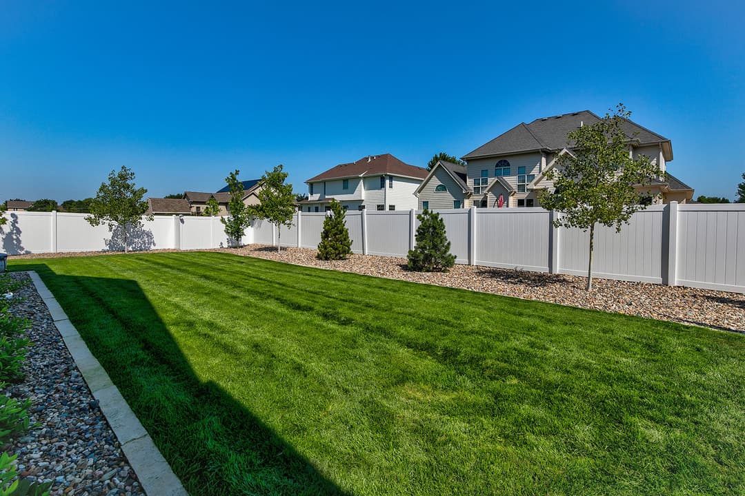Lush green backyard with privacy fence and landscaped edges in a residential neighborhood.