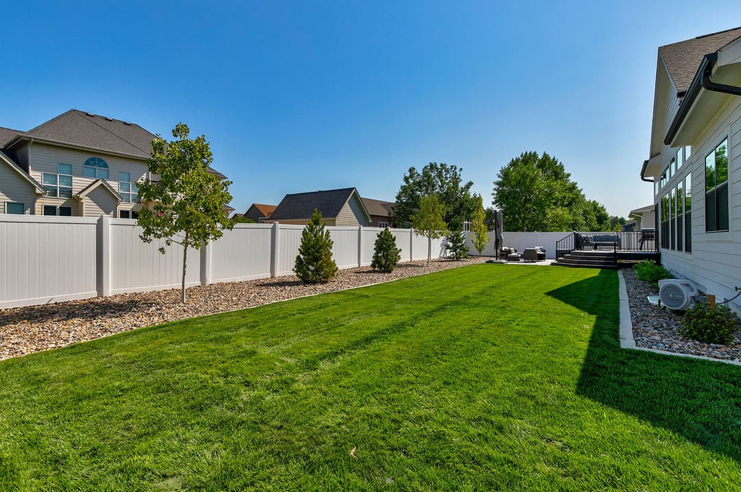 Lush green backyard with modern landscaping and fencing, ideal for outdoor activities.