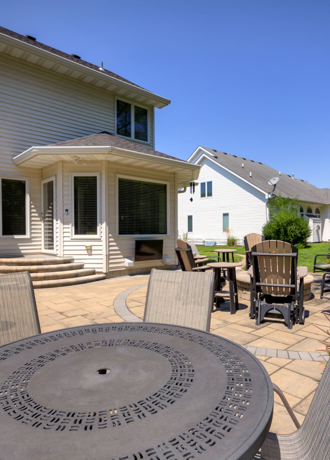 Modern patio set with a view of a house and clear blue sky, perfect for outdoor gatherings.