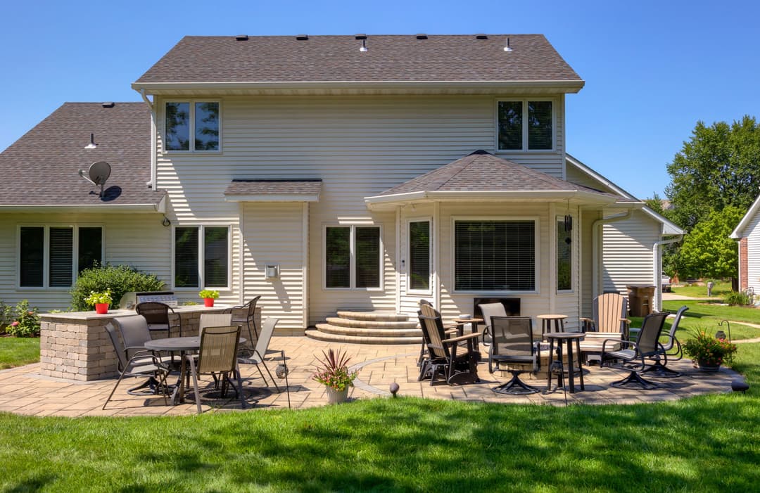 Modern home with patio seating, outdoor kitchen, and well-maintained garden in sunny backyard.