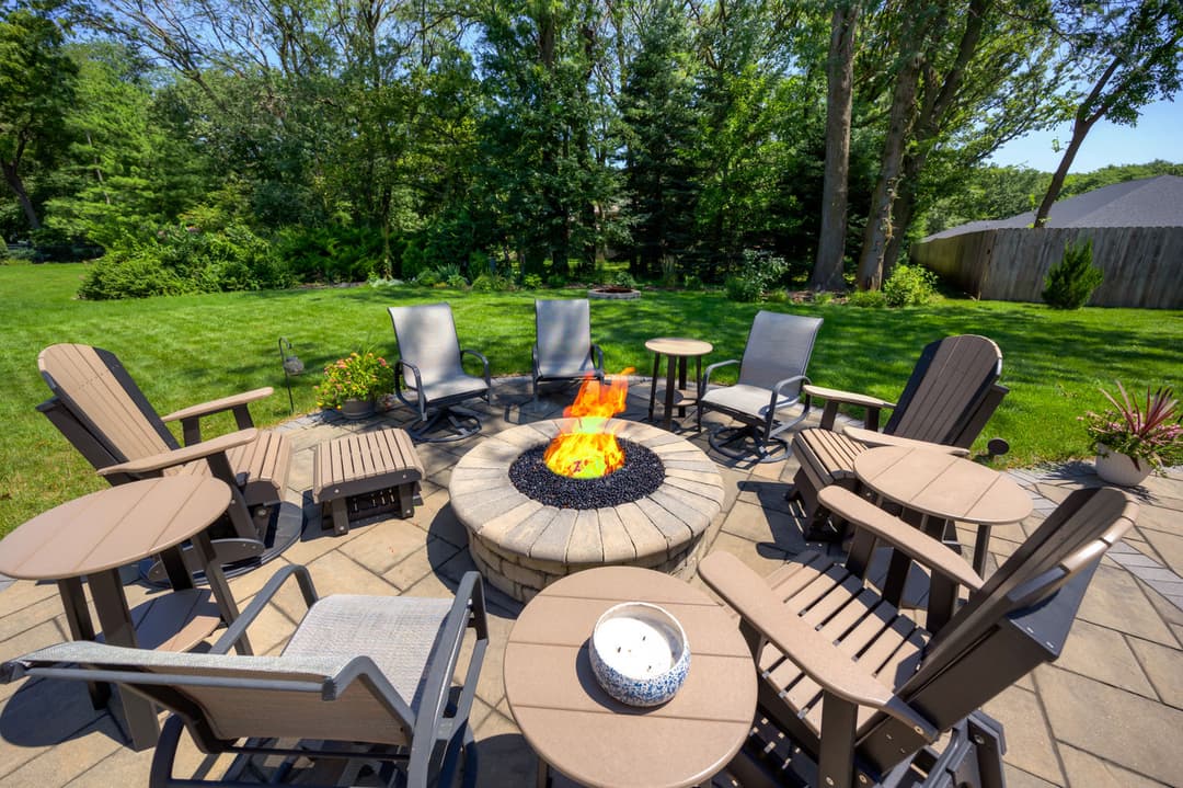 Outdoor fire pit surrounded by comfortable seating in a green garden setting. Perfect for gatherings.