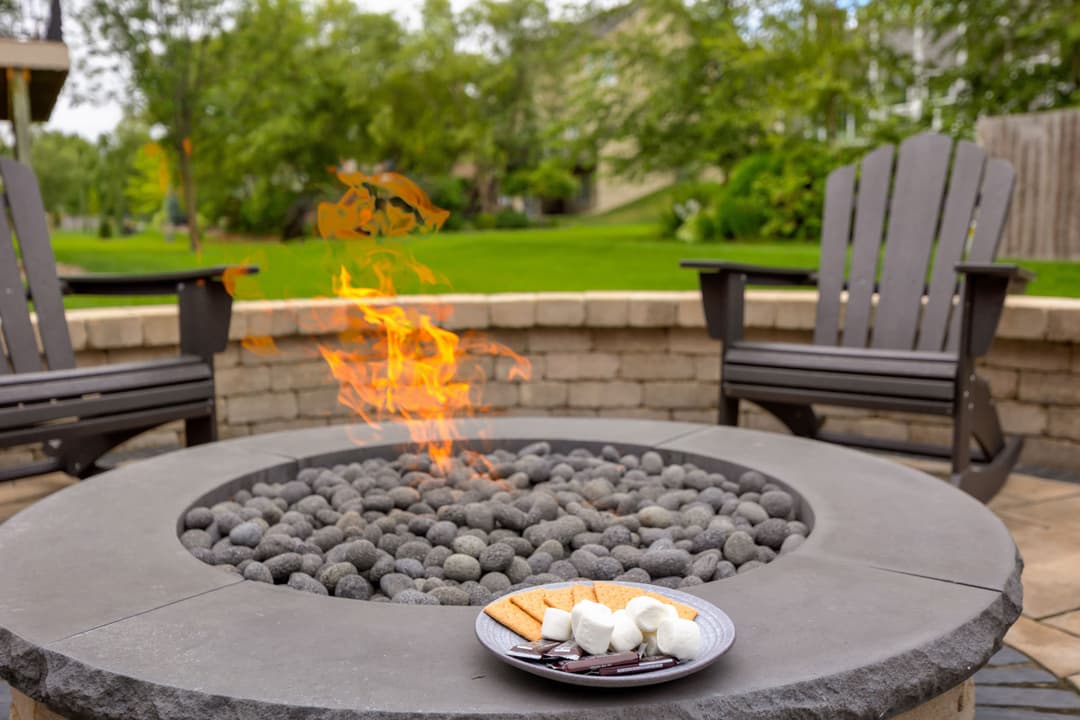 Fire pit with roasted marshmallows and graham crackers in backyard setting.
