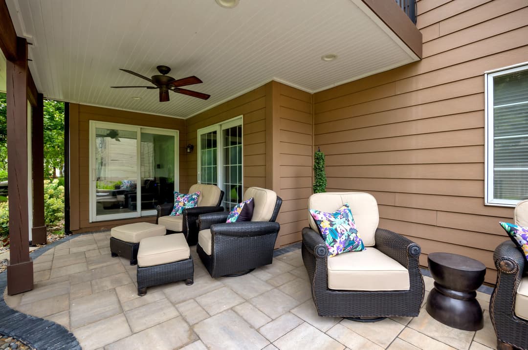 Cozy outdoor patio with wicker chairs, colorful cushions, and stone flooring. Ideal for relaxation.