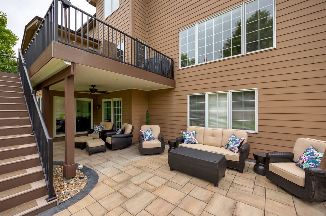 Stylish outdoor living space with seating, pillows, and a staircase in a modern home.