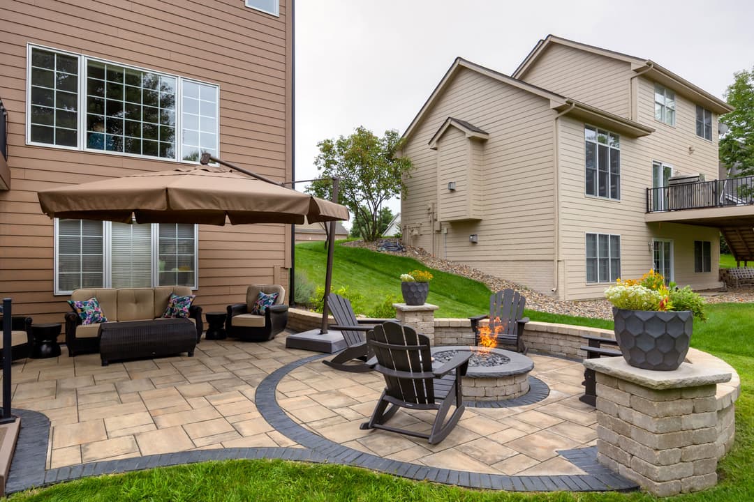 Cozy backyard patio with fire pit, seating area, and landscaping in a residential setting.