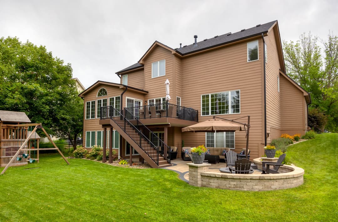 Modern two-story home with landscaped yard, patio, and outdoor seating area.