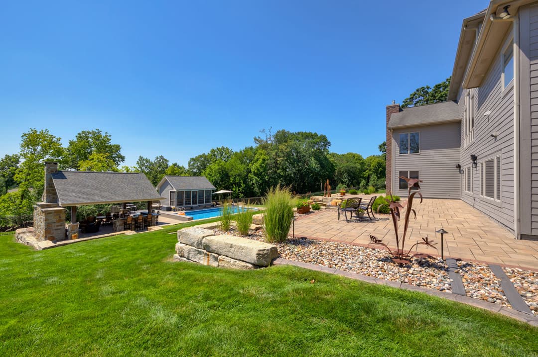 Luxury backyard oasis with pool and patio, featuring landscaping and outdoor seating area.