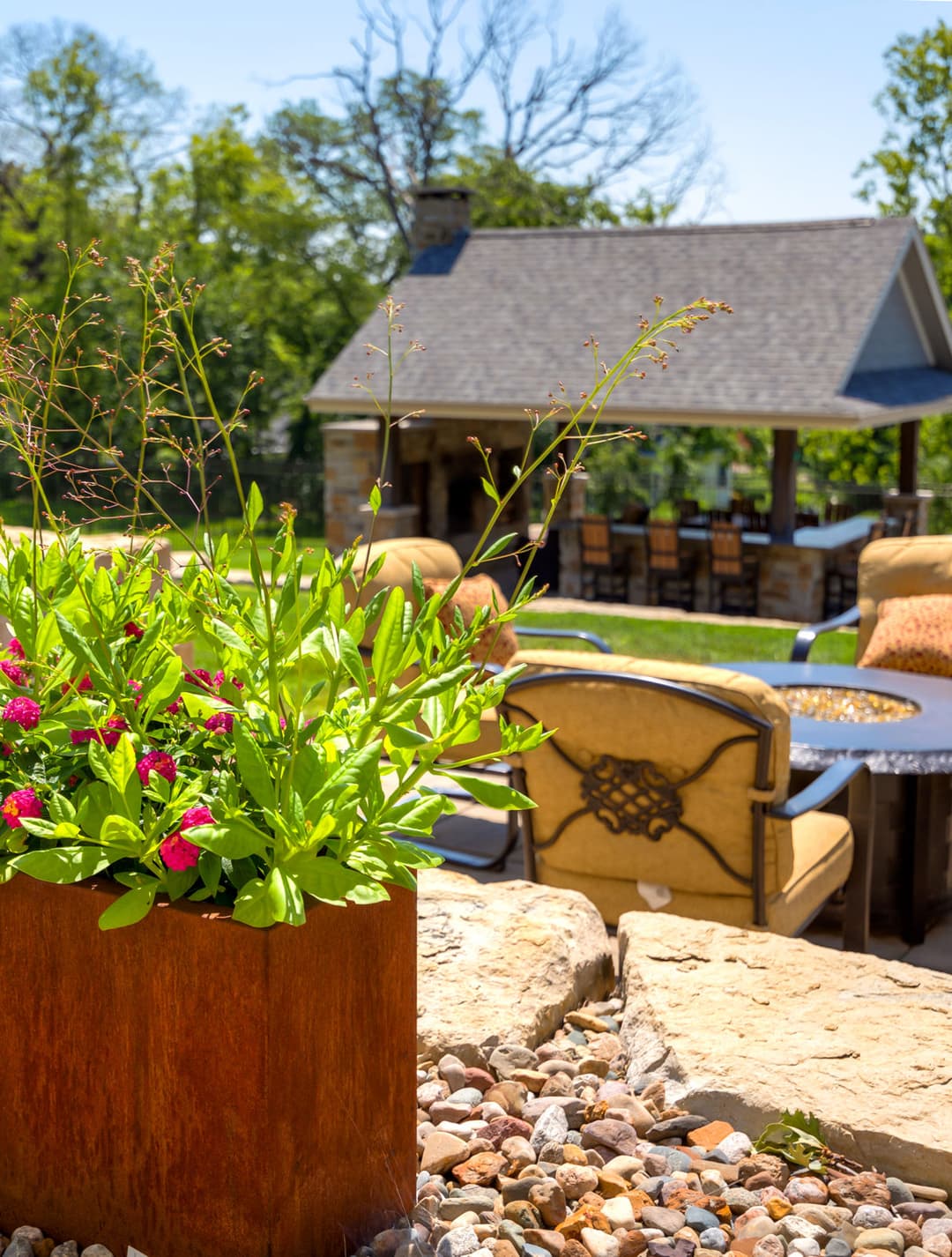 Vibrant flower planter in foreground with outdoor seating and gazebo in background.