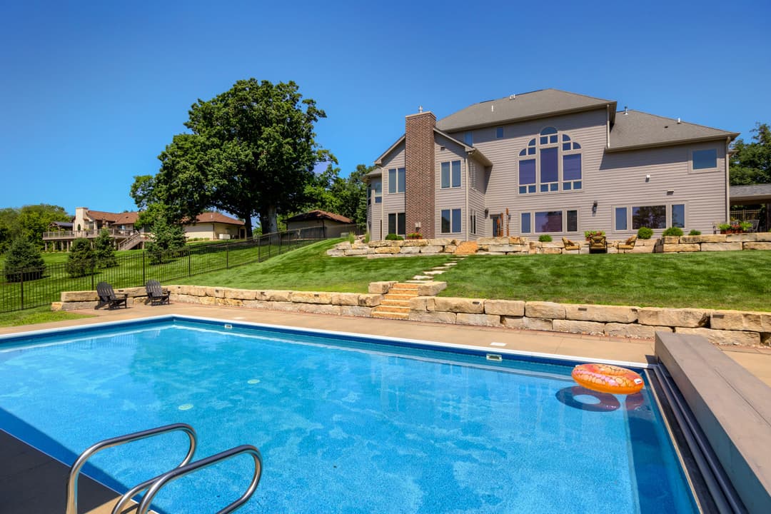 Beautiful backyard with a sparkling pool, lush lawn, and a modern home in the background.