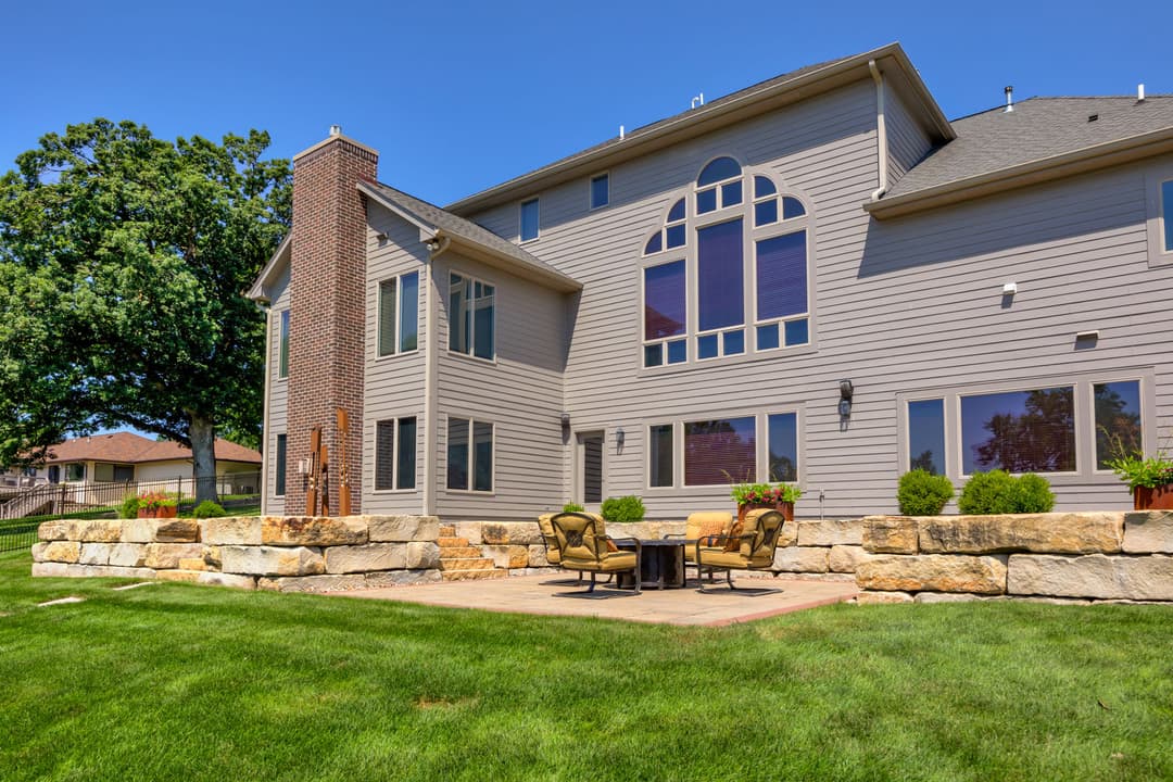 Spacious modern home with a stone patio, outdoor seating, and large windows.