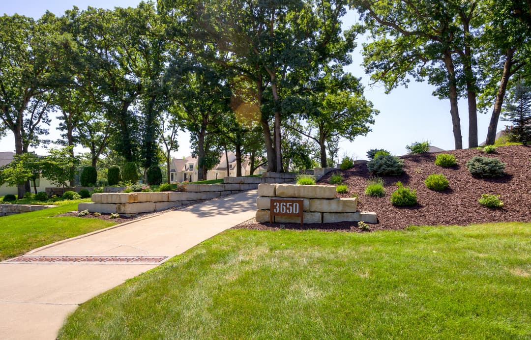 Driveway leading to home at 3650, surrounded by landscaped greenery and trees.