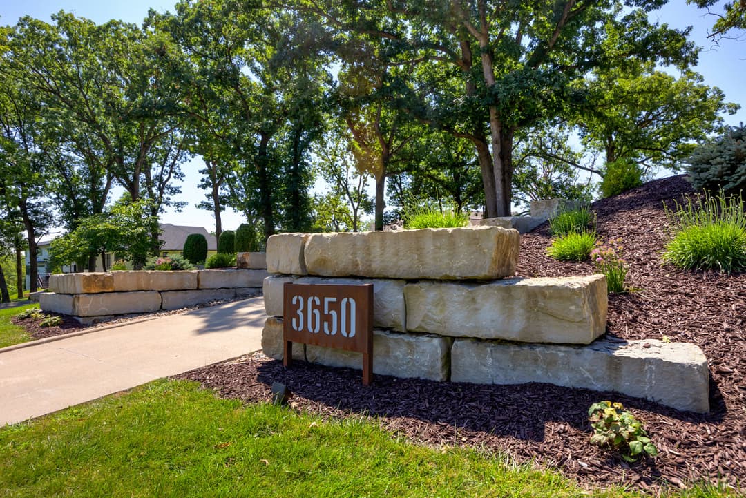 Stone entrance with address number 3650 surrounded by greenery and landscaping elements.