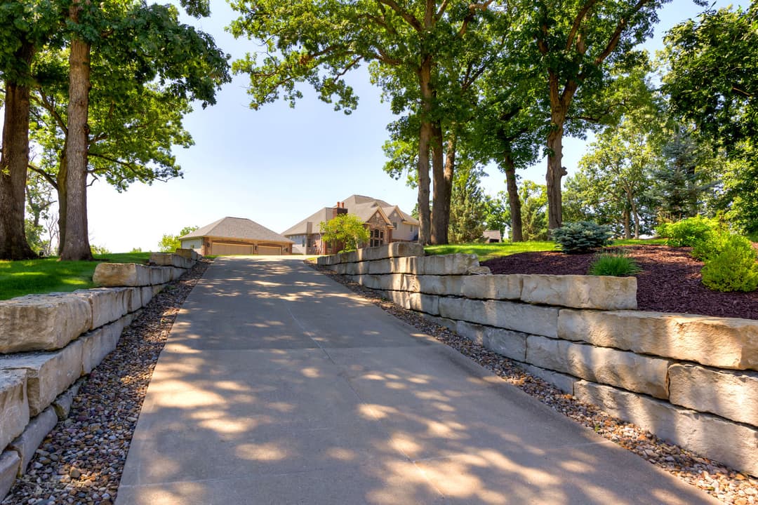 Inviting driveway lined with trees leading to a beautiful home on a sunny day.