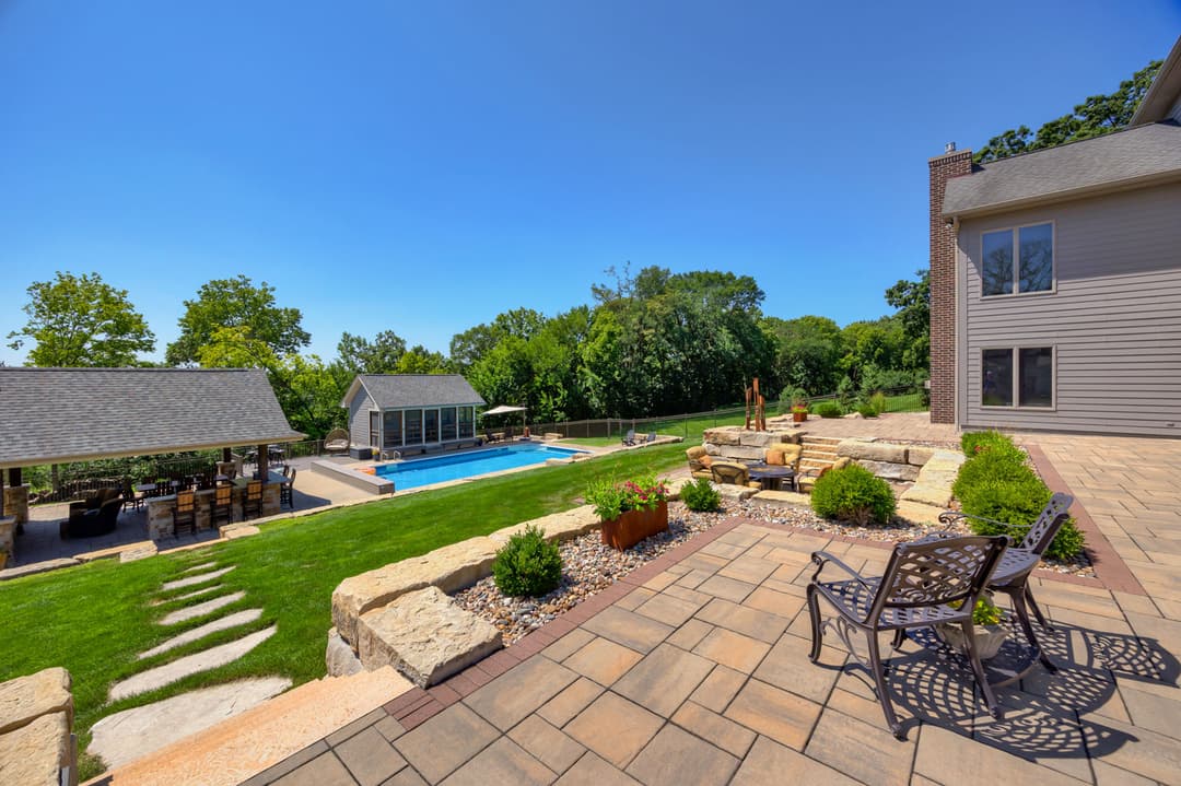 Scenic backyard with pool, patio, and landscaped greenery on a sunny day.