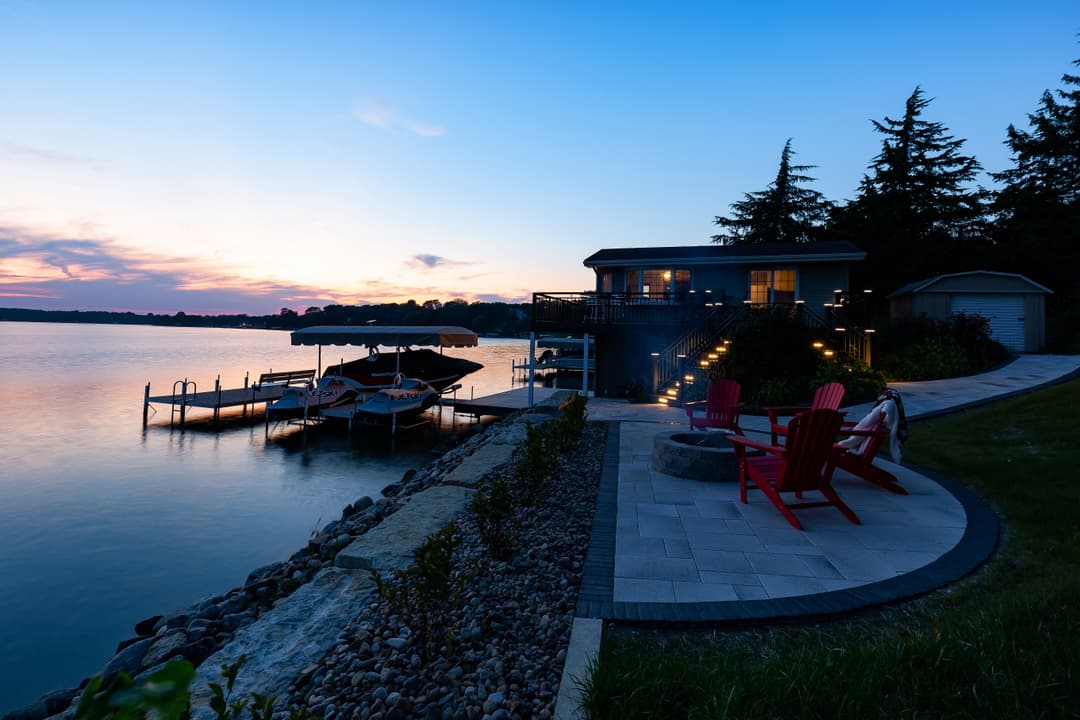 Sunset over a tranquil lake with a cozy dock, boats, and inviting outdoor seating area.