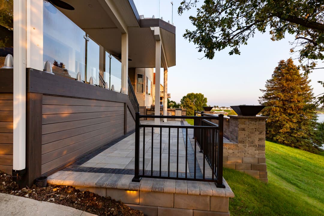 Modern outdoor patio with stone pavers, railings, and scenic lake view. Ideal for entertaining.