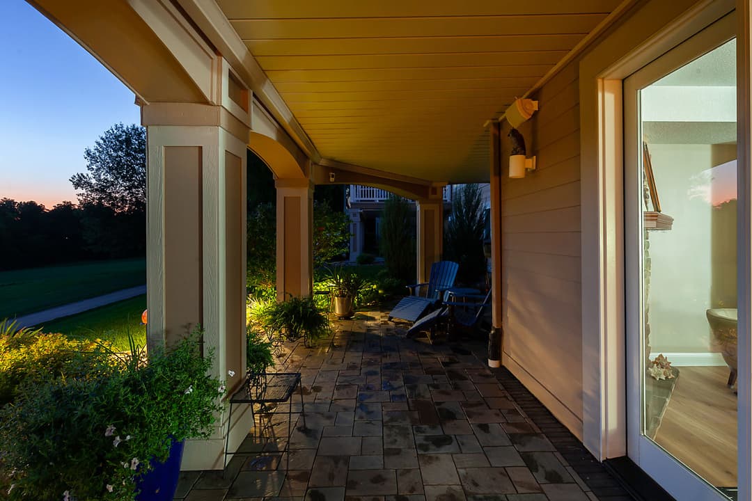 Cozy porch with ambient lighting, stylish chairs, and lush greenery at dusk.