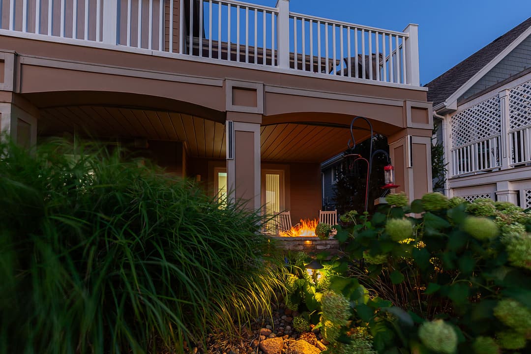 Cozy outdoor seating with a fire pit, surrounded by lush greenery at dusk.