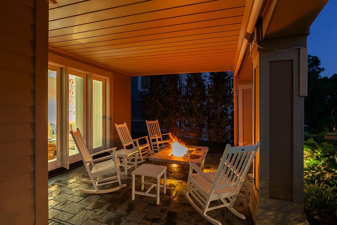 Outdoor living space featuring rocking chairs and a fire pit, warmly lit for cozy gatherings.