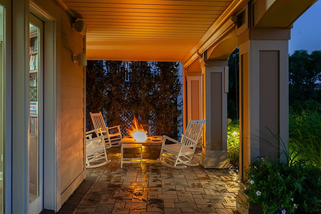 Cozy outdoor patio with rocking chairs and a glowing fire pit at twilight.