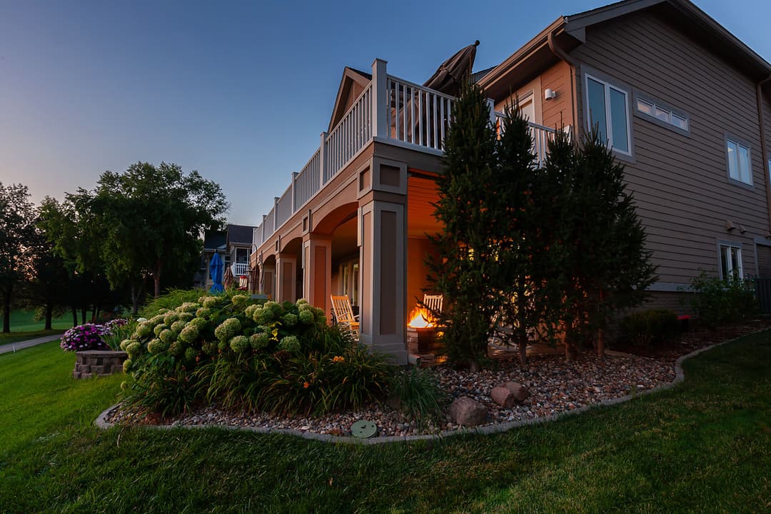 Cozy home exterior at dusk with vibrant flowers and a welcoming porch.
