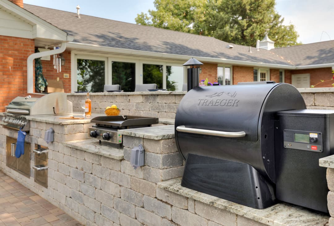 Outdoor kitchen with Traeger grill and stone counter, perfect for summer barbecues.