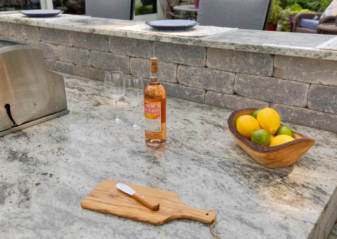 Outdoor kitchen with a bottle of rosé, glasses, and a wooden bowl of citrus fruits.