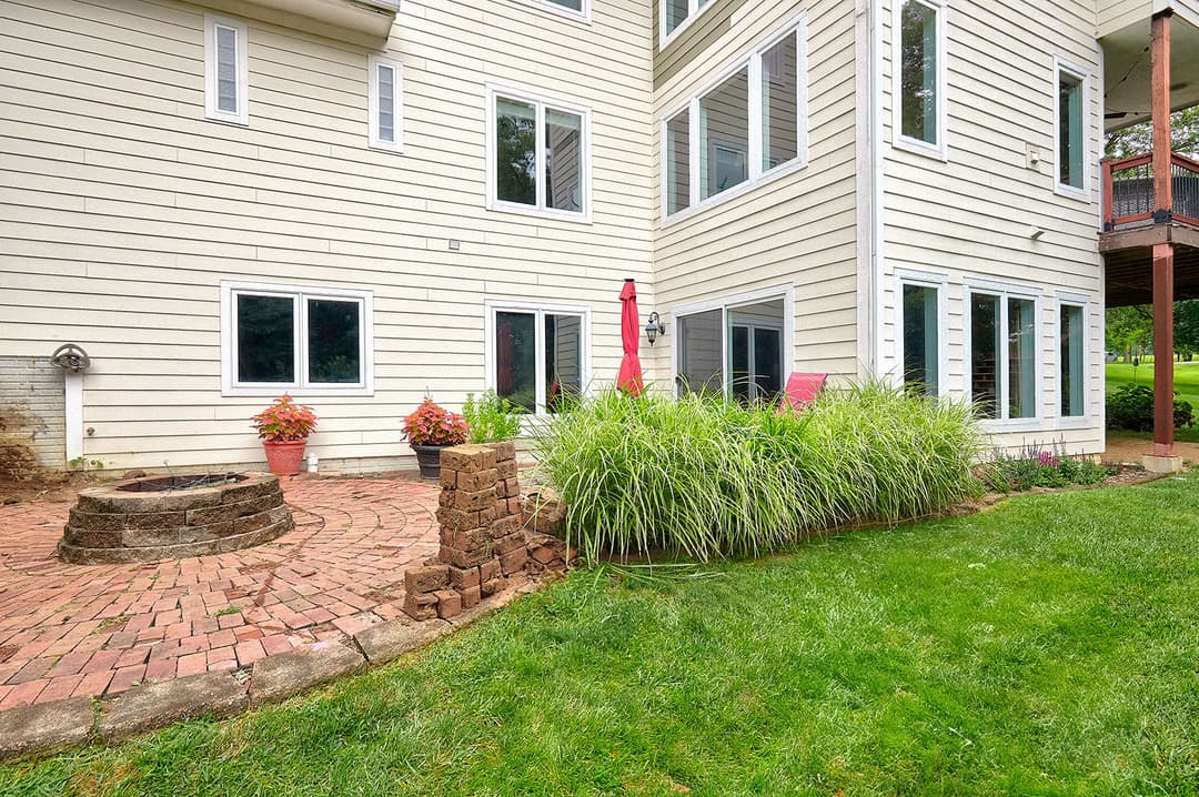 Exterior view of a home with a patio, fire pit, and landscaped garden area.