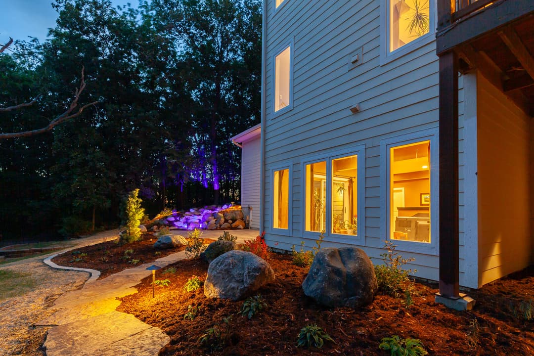 Cozy home exterior at dusk with landscaped garden and illuminated windows.