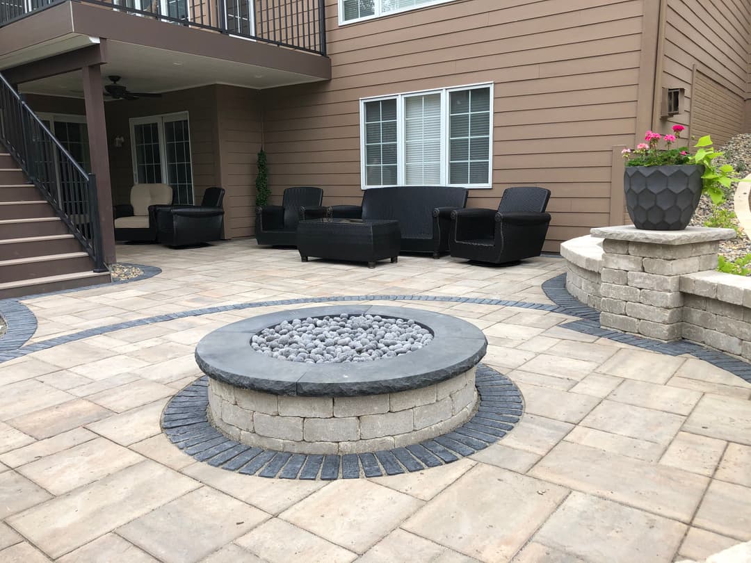 Modern outdoor patio with seating area, fire pit, and landscaped stone features.