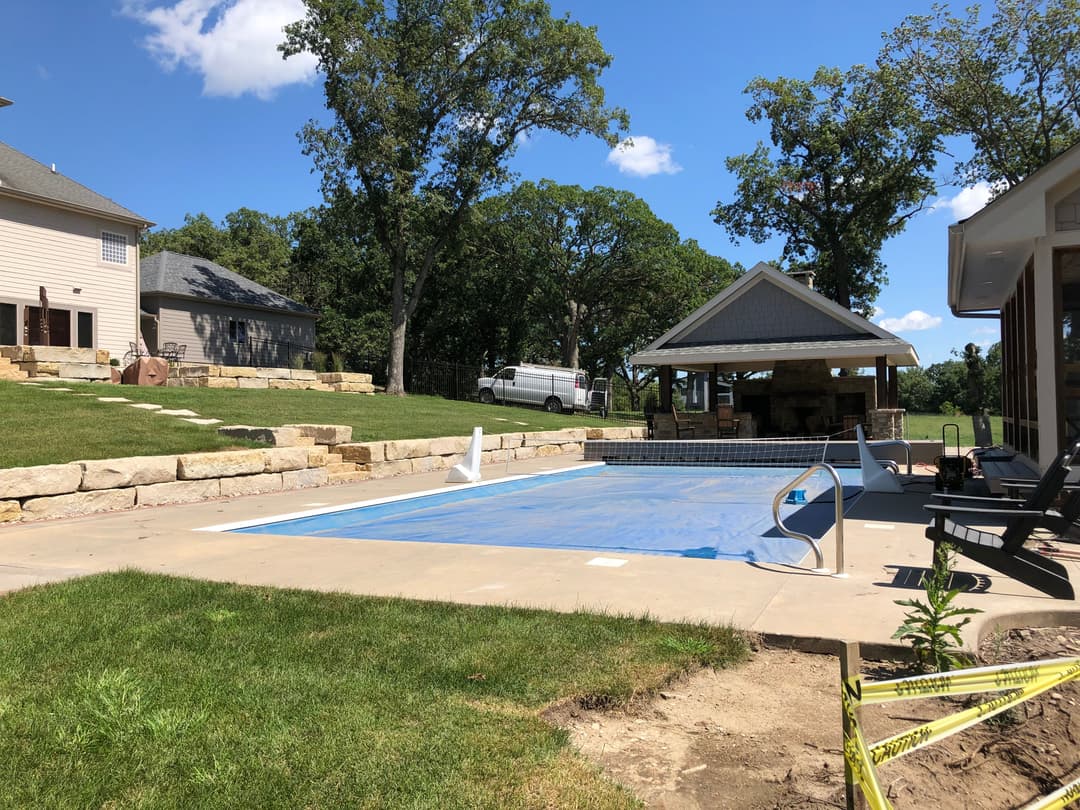 Outdoor swimming pool with lounge chairs and gazebo in a landscaped backyard setting.