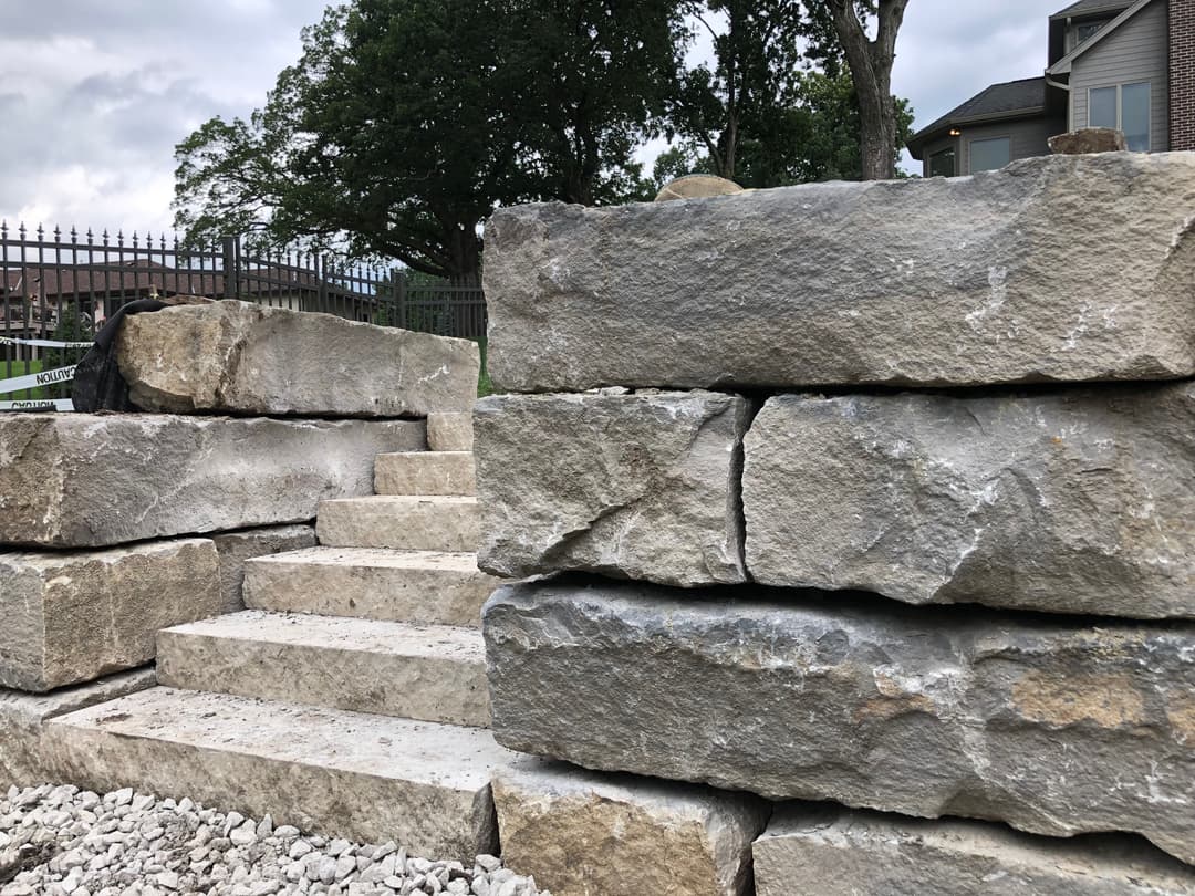 Stone steps leading up through large limestone blocks in a landscaped area.