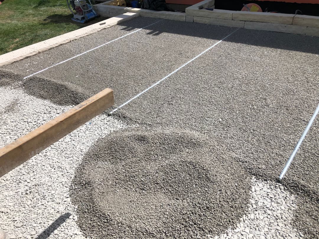 Gravel area preparation with a wooden level for landscaping project on a sunny day.