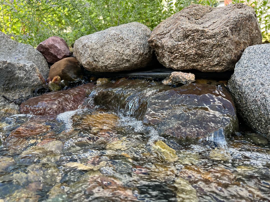 Flowing water over rocks in a serene natural setting, enhancing outdoor tranquility.