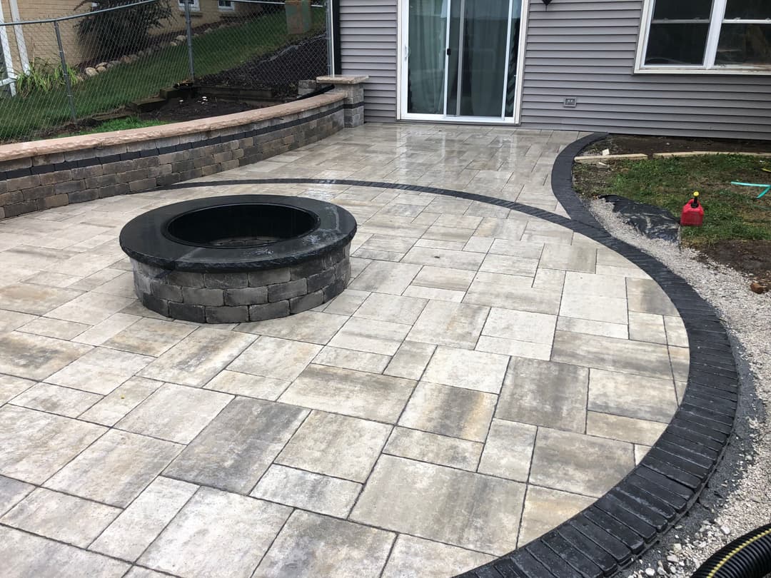 Patio with circular stone fire pit and elegant paver design for outdoor relaxation.