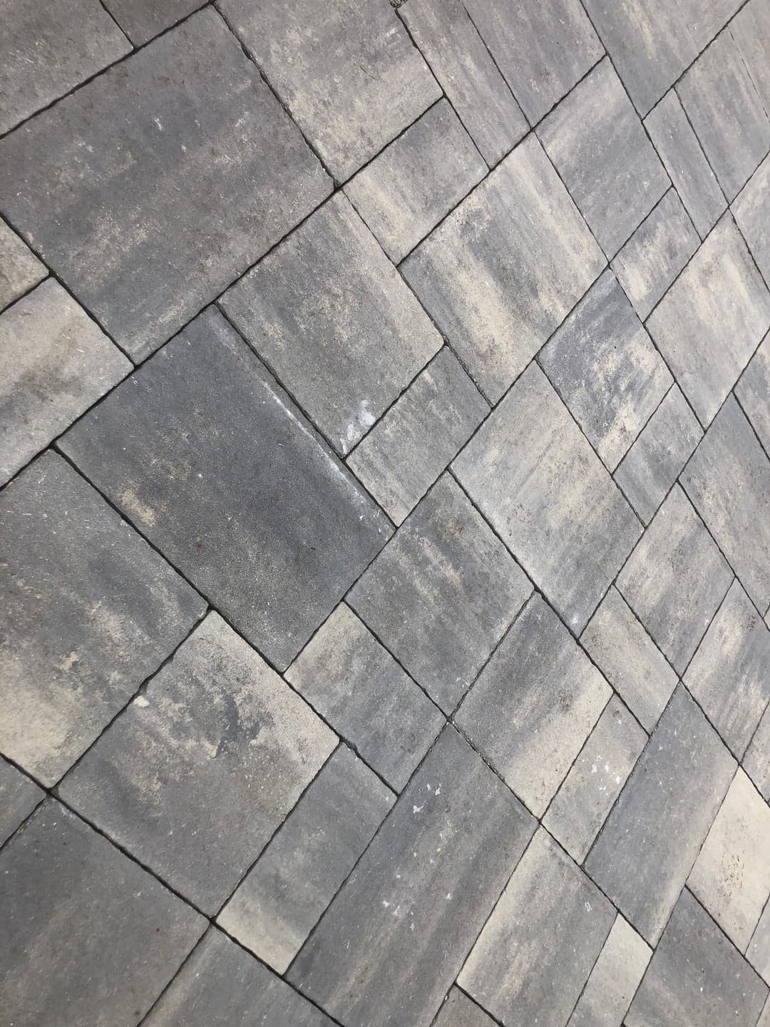 Gray interlocking pavers arranged in a diagonal pattern on a surface.