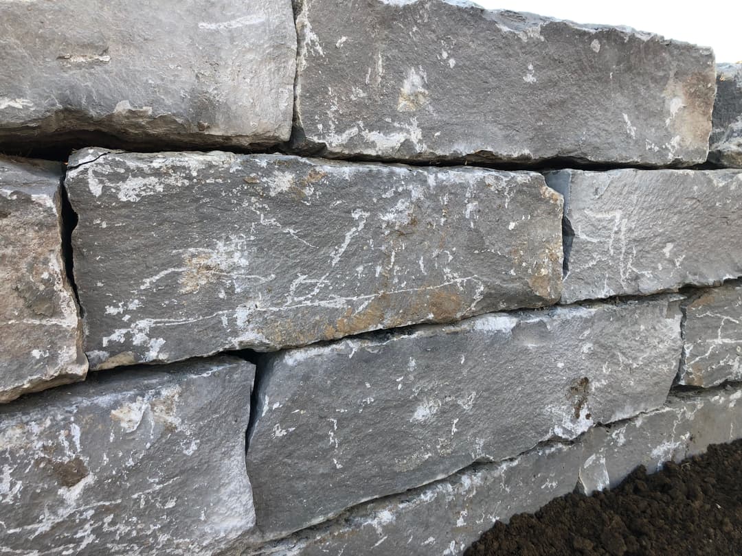 Gray stone wall with distinct texture and interlocking natural stones. Perfect for landscaping.