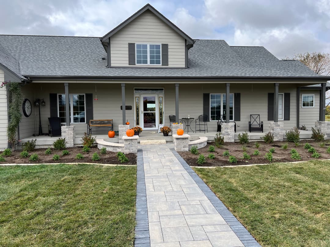 Modern farmhouse with landscaped front yard, stone pathway, and fall decorations.