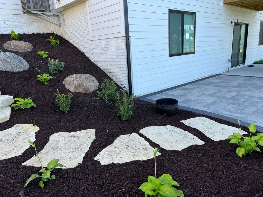 Landscape design with stone pathway, greenery, and modern home exterior.