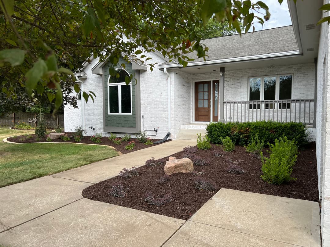 Modern home exterior with landscaped front yard, concrete pathway, and stone accents.