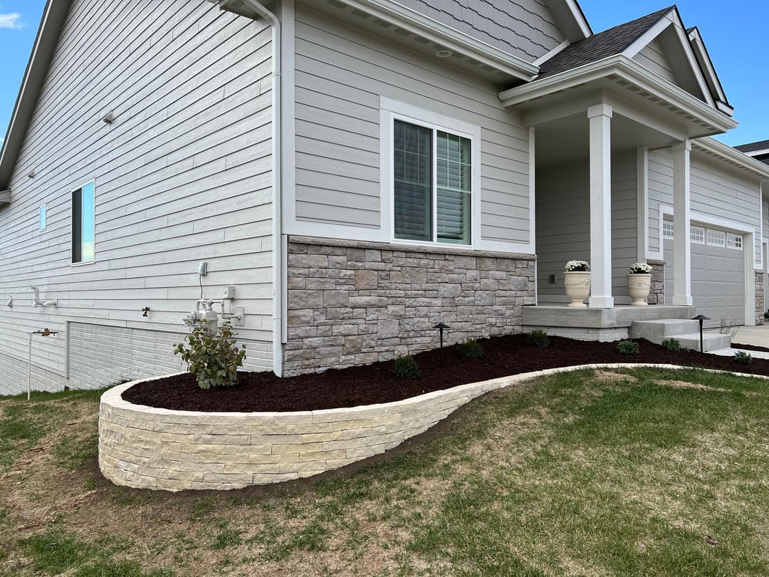 Modern home exterior with landscaped flower beds and stone accents.