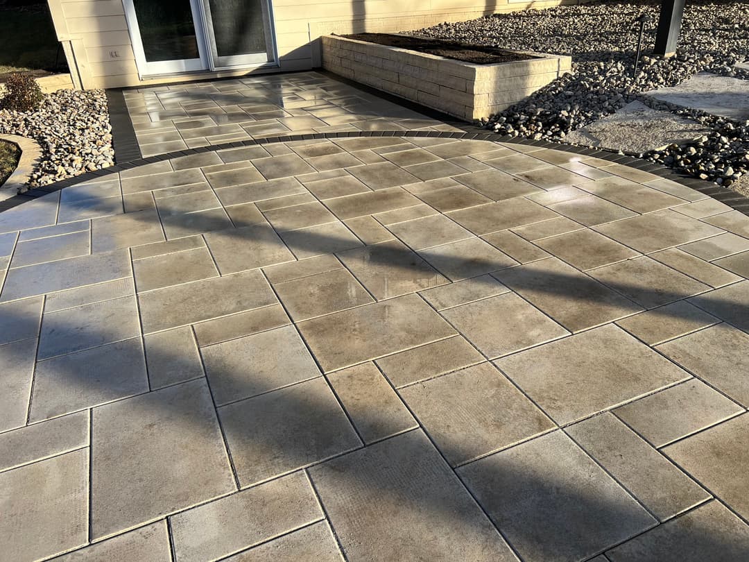 Paver patio with herringbone pattern and shadows, enhancing outdoor living space aesthetics.