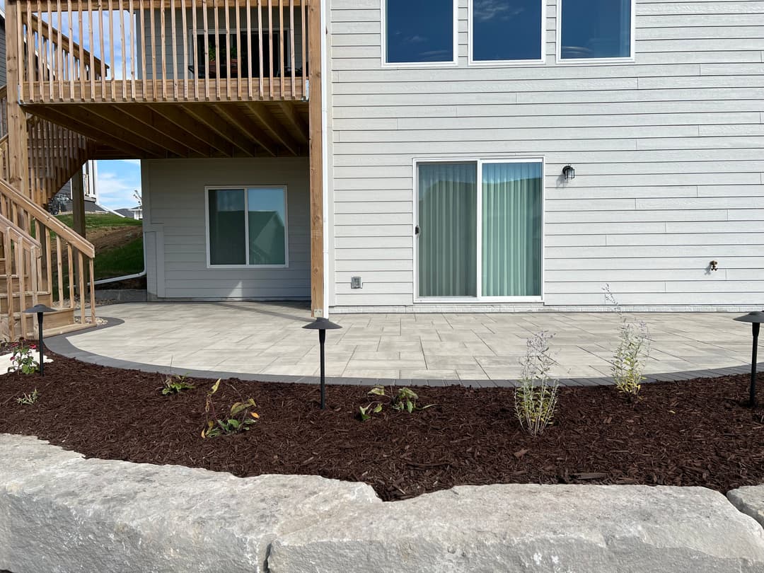 Modern home exterior with a patio, landscaped garden, and wooden deck.
