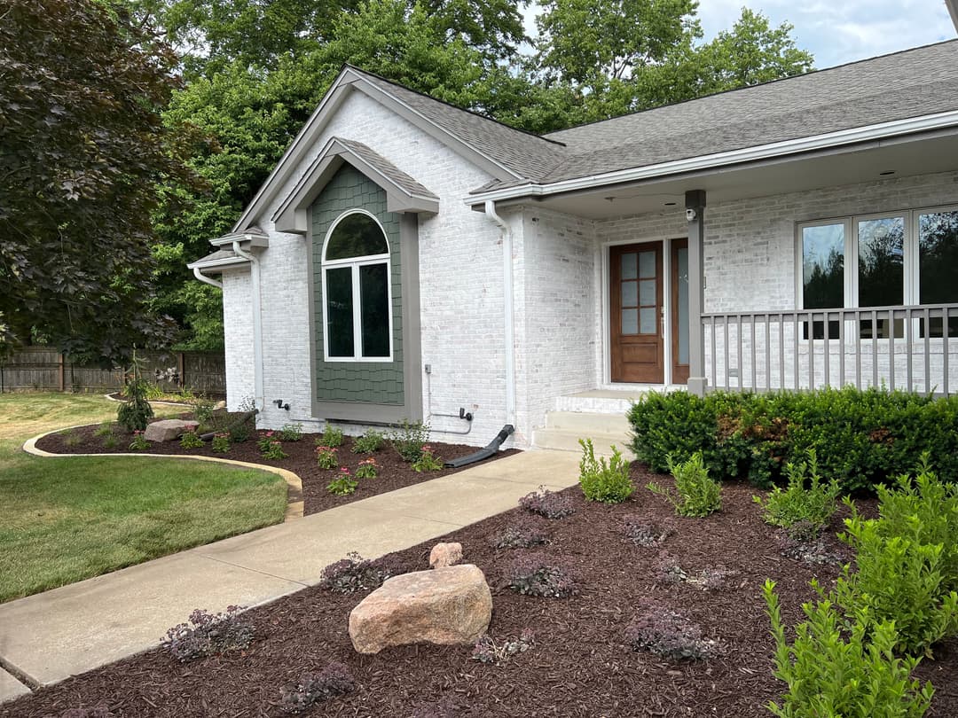 Modern white brick home with green accents and landscaped garden.