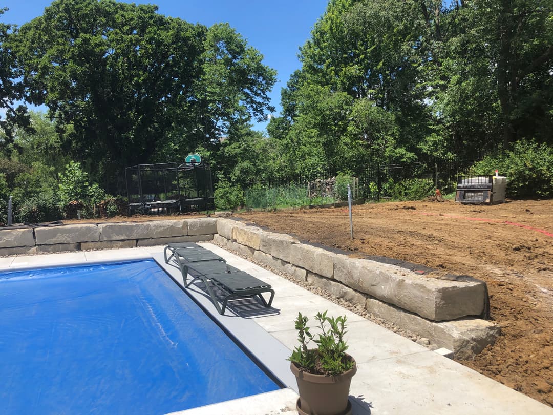 Backyard with a blue pool, lounge chairs, and a landscaped area in a serene garden setting.