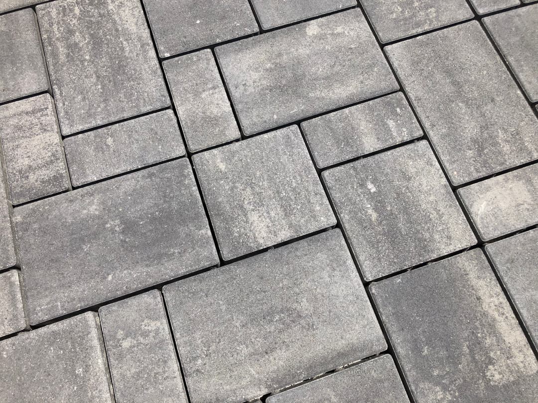 Gray textured paving stones arranged in a geometric pattern for outdoor surfaces.