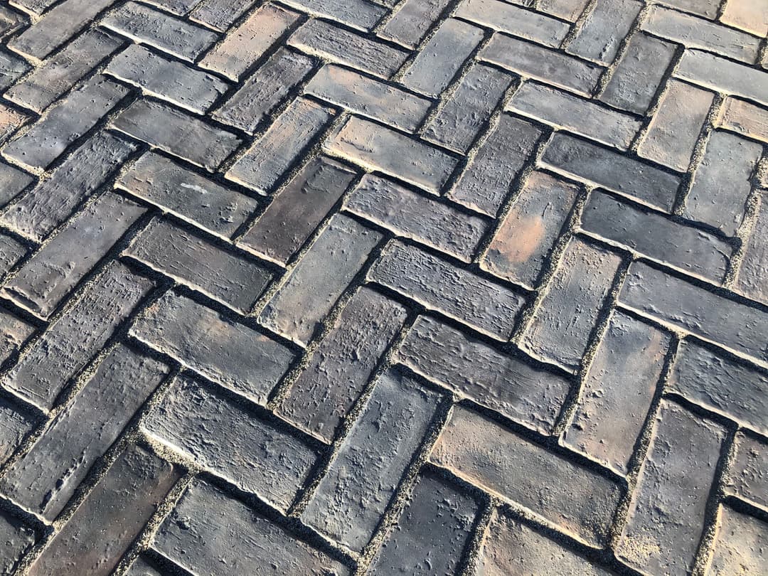 Herringbone patterned brick pavement with varied earthy tones and textures.